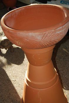 a large clay pot sitting on top of a cement floor next to a planter