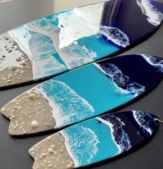 two surfboards with blue and white designs on them sitting on top of a table