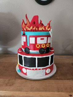 a fire truck cake on a wooden table with a clock in the backgroud