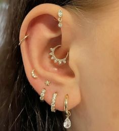 a woman wearing three different types of ear piercings