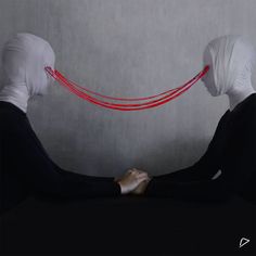 two women in white headscarves are facing each other with red string attached to them