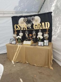 a table topped with vases and pictures under a tent covered in black and gold