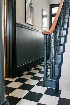 a black and white checkered floor next to a staircase with wooden handrails