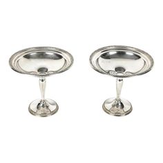 two silver candlesticks sitting on top of each other