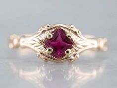 a close up view of a ring with a pink stone in it's center