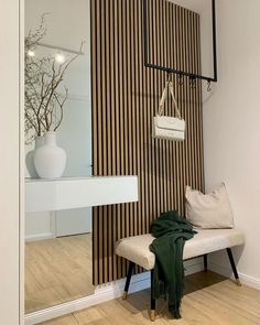 a white bench sitting in front of a wooden wall with a mirror on top of it