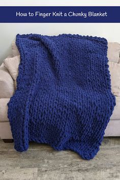 a blue knitted blanket sitting on top of a white couch