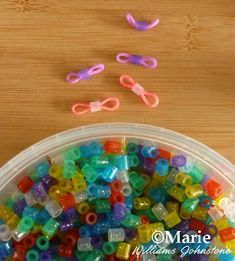 there are many small plastic beads in the container with scissors on the table next to it