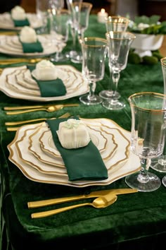 a table set with green velvet and gold place settings