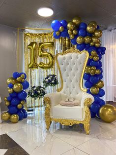 a chair and balloon arch in the middle of a room with blue and gold balloons