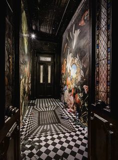 a room with black and white checkered flooring, walls painted with colorful designs