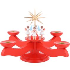 two figurines are on top of a red christmas tree with candles and a star