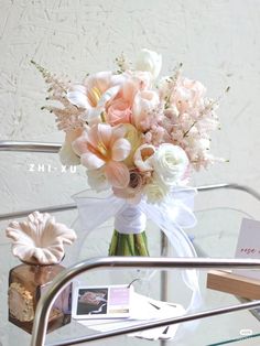 a bouquet of flowers sitting on top of a glass table next to a card holder