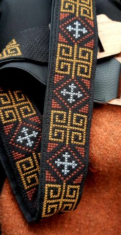 a close up of a black and yellow ribbon on a brown cloth with other items in the background