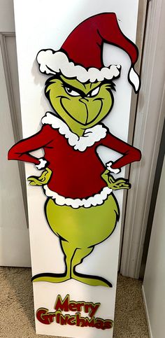 the grinch is standing in front of a christmas sign