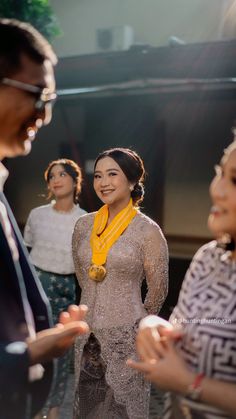 two women and one man are talking to each other while the woman is wearing a yellow scarf around her neck