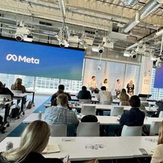 people are sitting at desks in front of a large screen