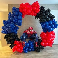 a spiderman balloon sculpture in the middle of a room with balloons all around it