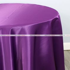 a purple table cloth on top of a wooden floor in front of a white wall