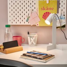 a desk with a lamp, notebooks and other office supplies on top of it