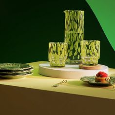 a table topped with plates and vases filled with fruit next to each other on top of a counter