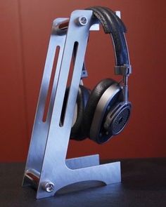 a pair of headphones sitting on top of a metal stand with red walls in the background