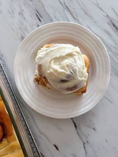 a white plate topped with a pastry covered in frosting next to a baking pan