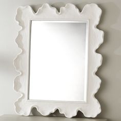 a white scalloped mirror sitting on top of a shelf