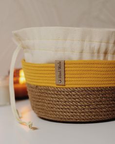 a yellow and white basket sitting on top of a table next to a lit candle