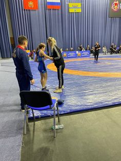 some people are standing on a trampoline in an indoor gym with blue tarps