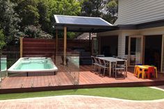 a hot tub sitting on top of a wooden deck next to a swimming pool in a backyard