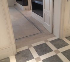 an empty room with white walls and black shelves on the wall next to a checkered floor