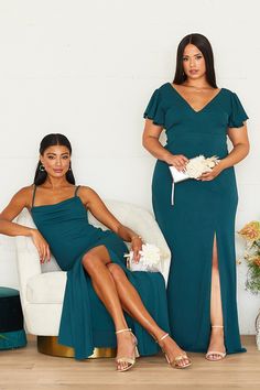 two women in green dresses sitting on a white chair and one is holding a bouquet