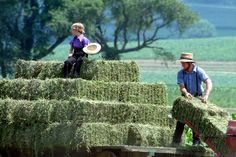 two people standing on top of hay bales