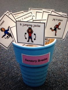 a cup filled with cards sitting on top of a table next to a blue bucket