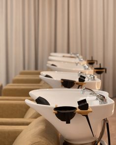 a row of white sinks sitting on top of a wooden floor next to a wall