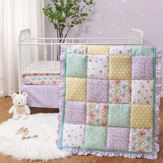 a baby crib with a teddy bear next to it and a flowered quilt on the bed