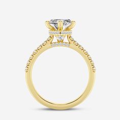 a yellow gold engagement ring with an oval cut diamond center and pave set shoulders