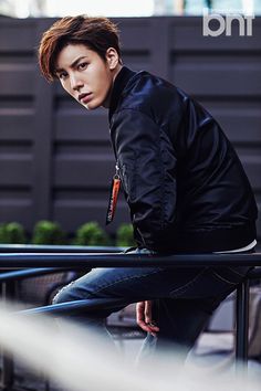 a young man sitting on top of a metal rail next to a building and looking at the camera