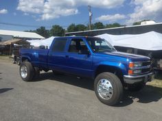 a blue pick up truck parked in front of tents