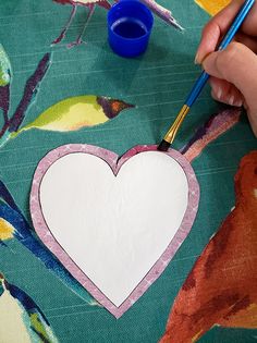 someone is making a paper heart with a paintbrush