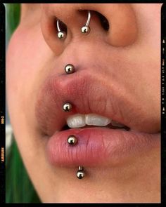 a woman's nose with piercings on it and her tongue in the middle