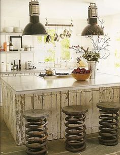 a kitchen island with three stools in front of it and two lights hanging from the ceiling