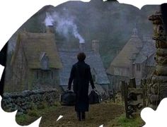 a man walking down a dirt road next to houses