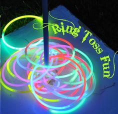 glowing neon rings are on the ground in front of a sign that says ring toss