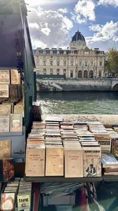 there are many books on display at the book stand by the river in front of an old building