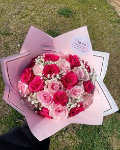 someone holding a bouquet of pink and white flowers in their hand on the grass outside