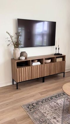 a living room with a large flat screen tv mounted on the wall above a wooden entertainment center