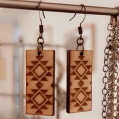 two wooden earrings hanging from chains in a room with other items on the wall behind them