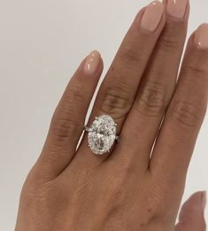 a woman's hand with a diamond ring on top of her finger and the other hand holding an engagement ring